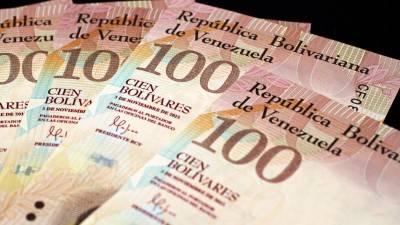 Venezuelanos distribuem notas de bolívares em troca de moedas em Bogotá